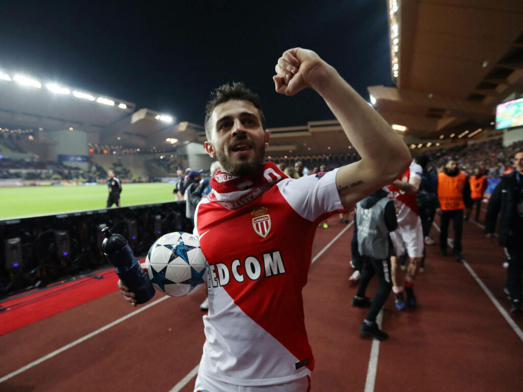 Bernardo Silva celebrating with ball in AS Monaco jersey in lively stadium football victory Wallpaper