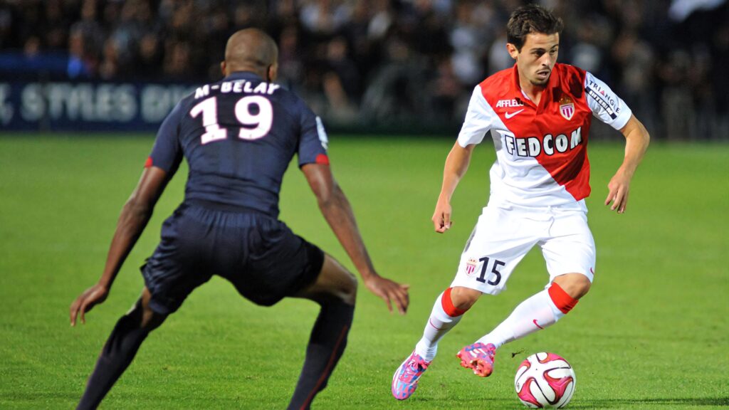 Bernardo Silva dribbling past defender showcasing agility and skill in intense football match Wallpaper