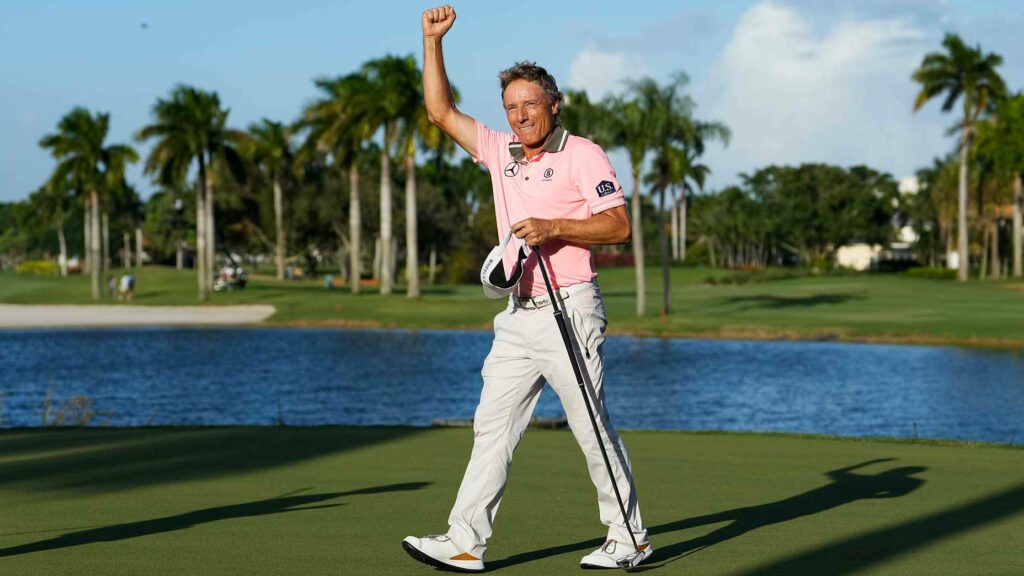 Bernhard Langer celebrating victory on scenic golf course with palm trees and blue water background Wallpaper
