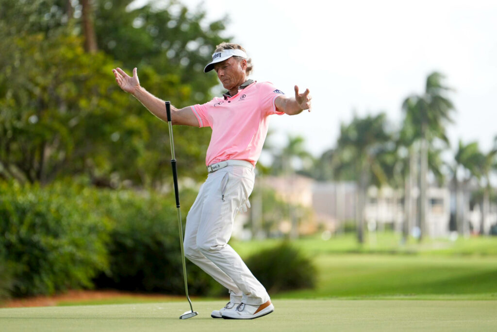 Bernhard Langer celebrates successful putt on lush golf course with palm trees and bright sky Wallpaper