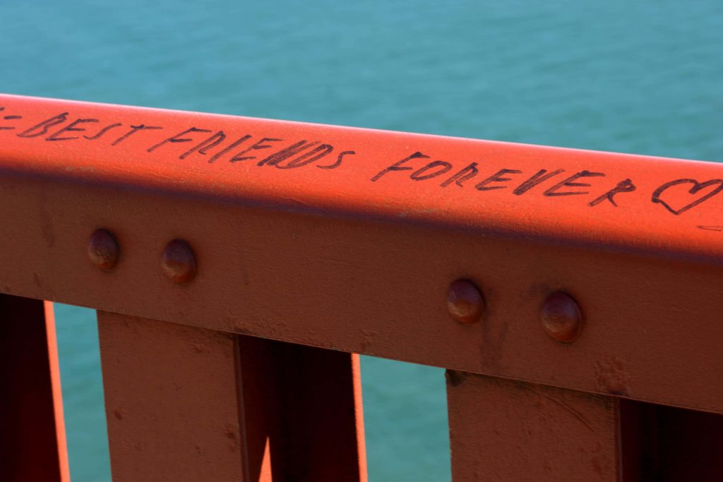 Close-up of Golden Gate Bridge orange railing engraved BEST FRIENDS FOREVER turquoise bay background Wallpaper