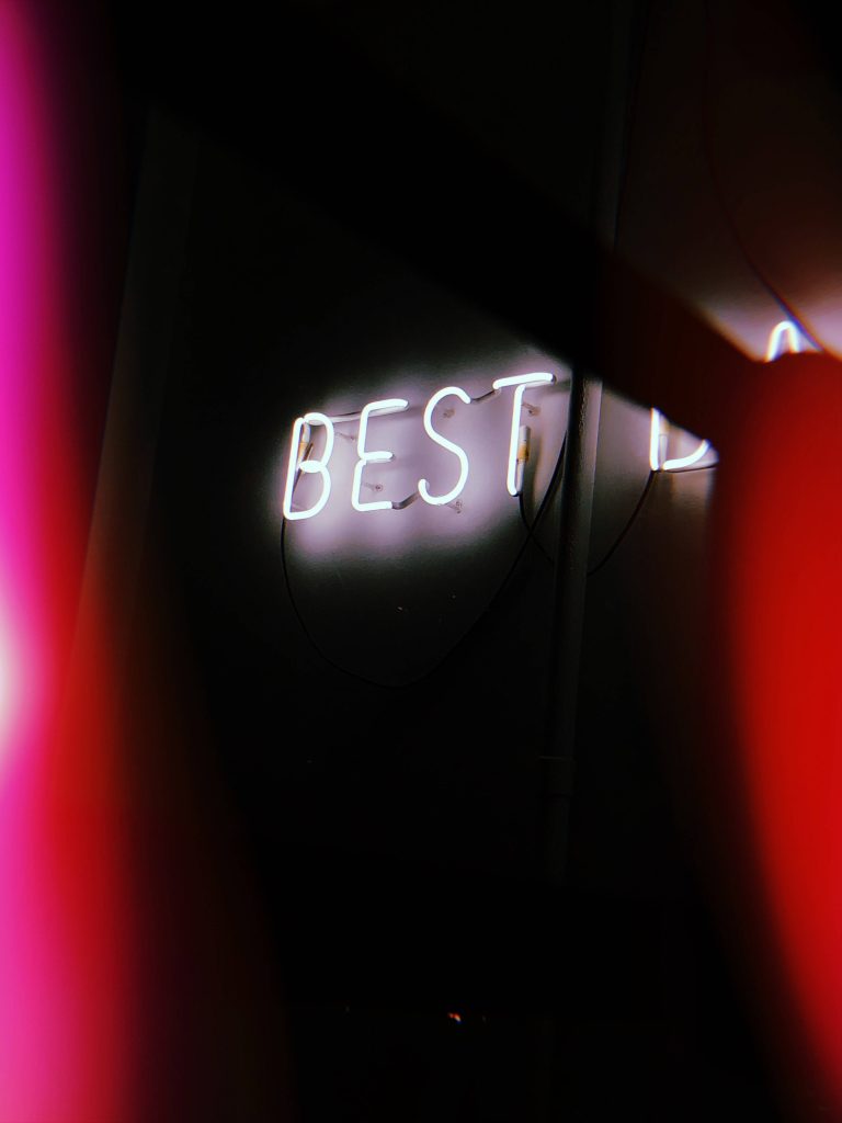 High-contrast Best LED signage wallpaper glowing white text on dark background with red silhouettes