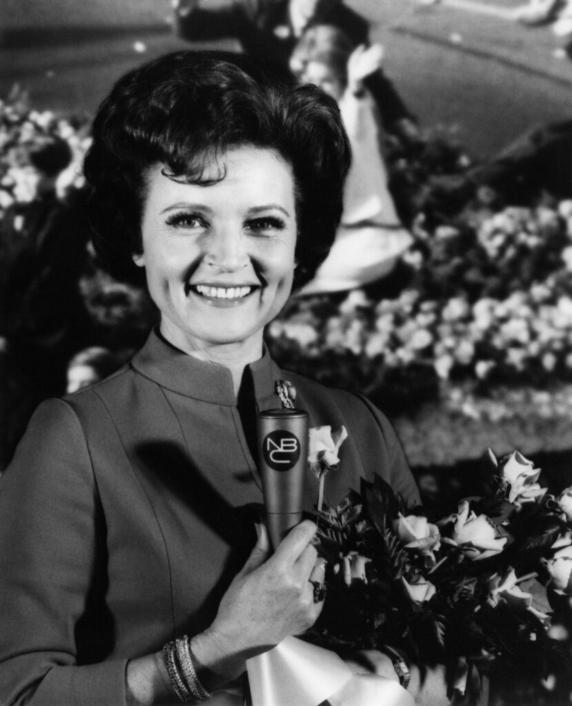 Betty White smiling holding roses and microphone at festive Tournament of Roses parade background Wallpaper