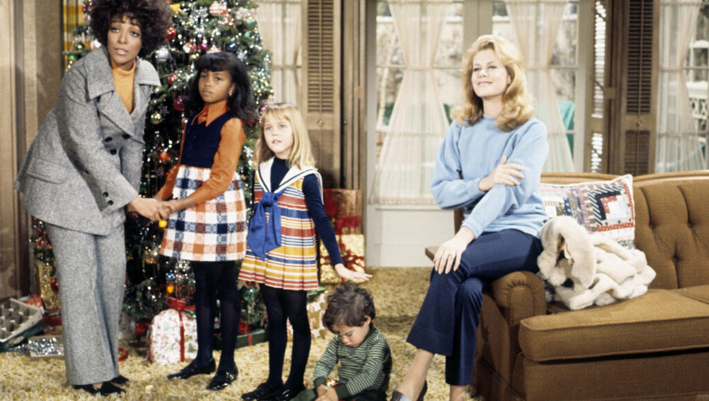 Bewitched cast celebrating Christmas together by a decorated tree festive holiday spirit wallpaper