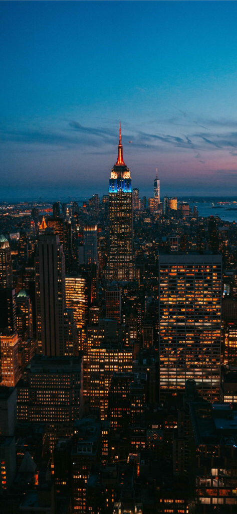 Enchanting Glow: The Iconic Empire State Building Shining Amidst New York's Vibrant Urban Nightscape Wallpaper