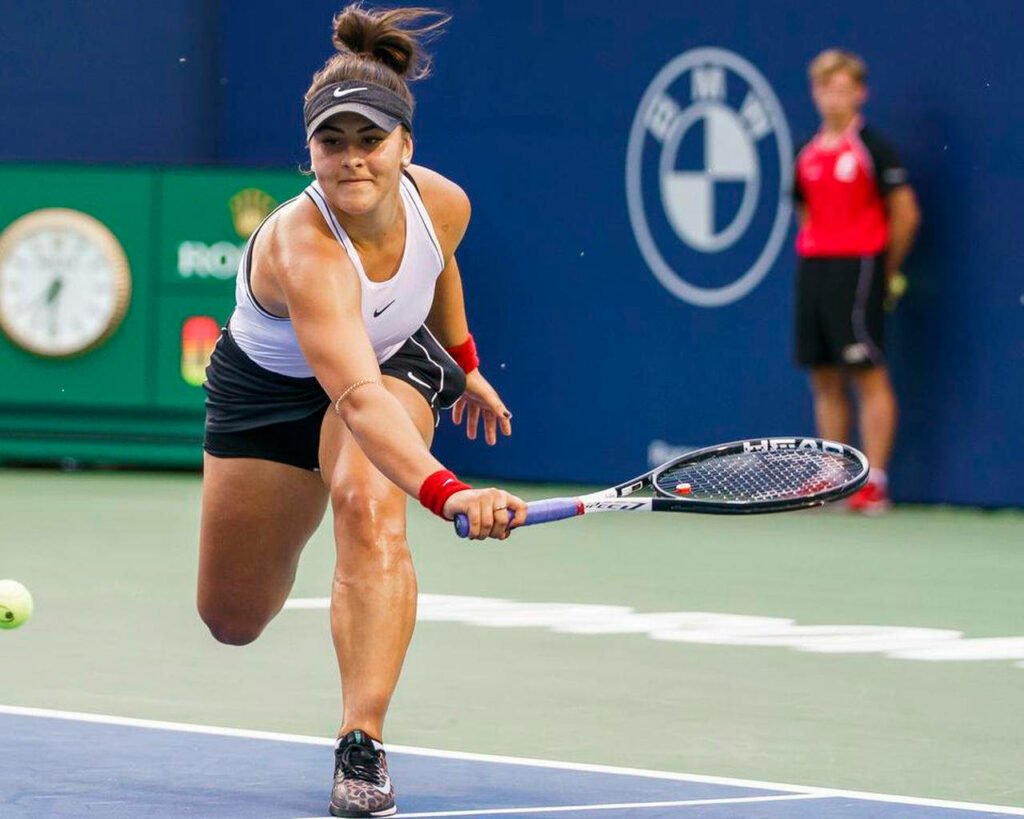 Bianca Andreescu stretching to hit tennis ball showing strength and determination on court wallpaper