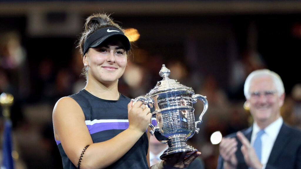 Bianca Andreescu celebrating tennis victory holding trophy smiling on court with cheering crowd Wallpaper