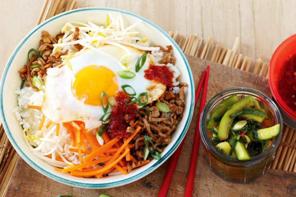 Bibimbap Bliss: A Mouth-Watering Korean Delight Served with a Side of Tangy Pickled Mustard Leaves Wallpaper