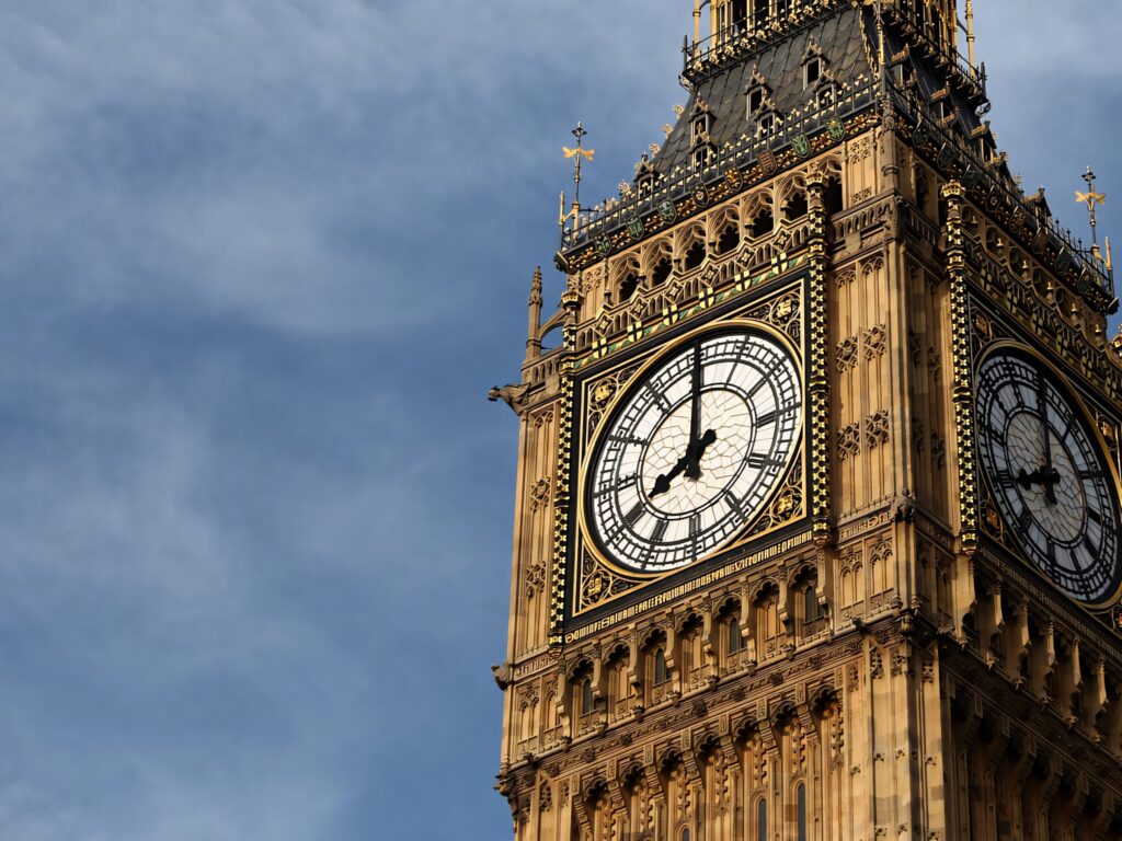 Big Ben clock tower illuminated by natural light showcasing detailed architecture and shadows Wallpaper