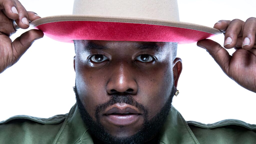 Close-up of Big Boi adjusting stylish hat confident expression white background wallpaper