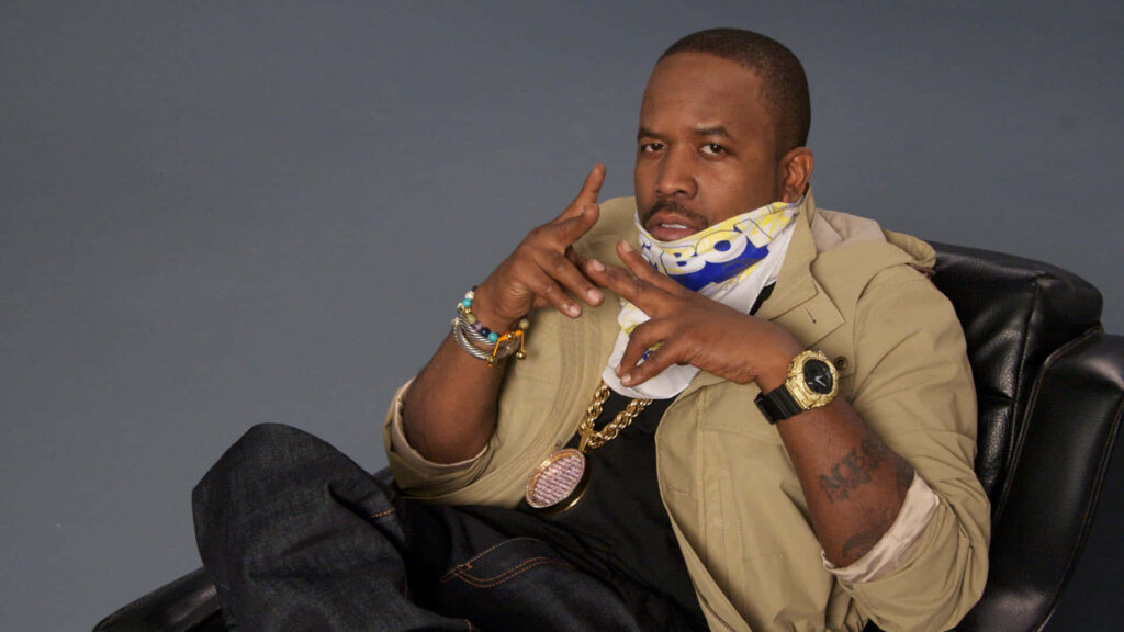 Big Boi confident in chair wearing stylish chain and accessories iconic hip hop wallpaper background
