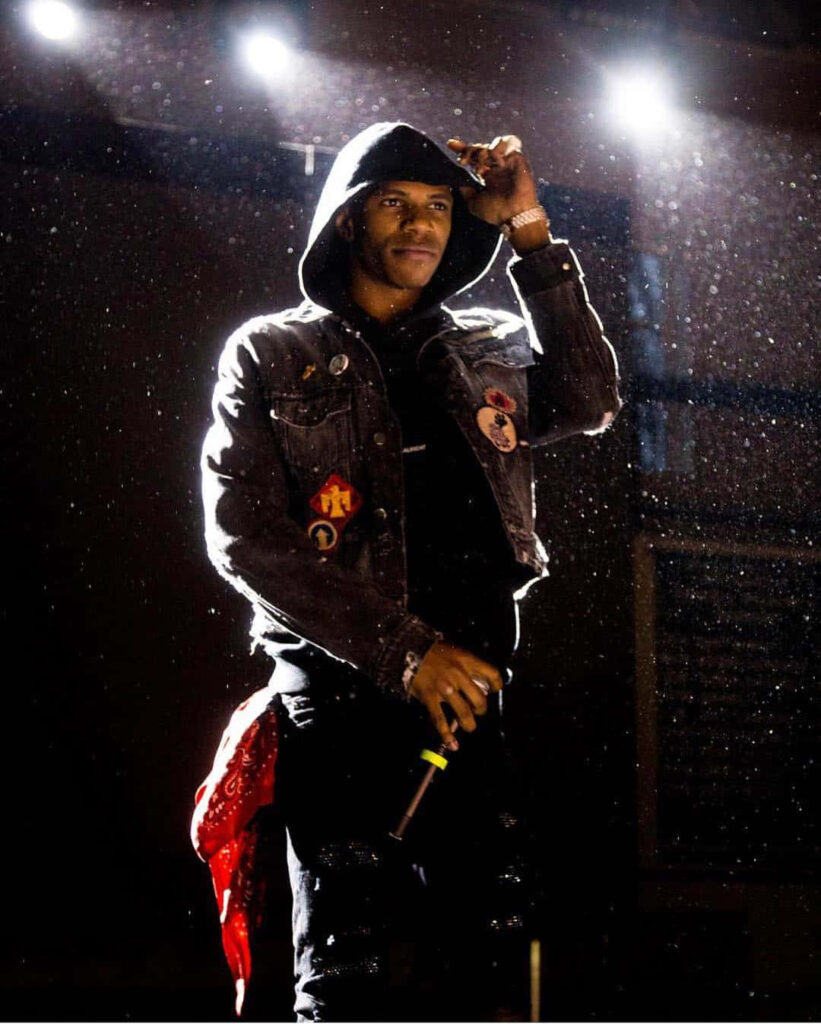 Big Boogie on stage with microphone dramatic lighting hooded jacket powerful concert wallpaper