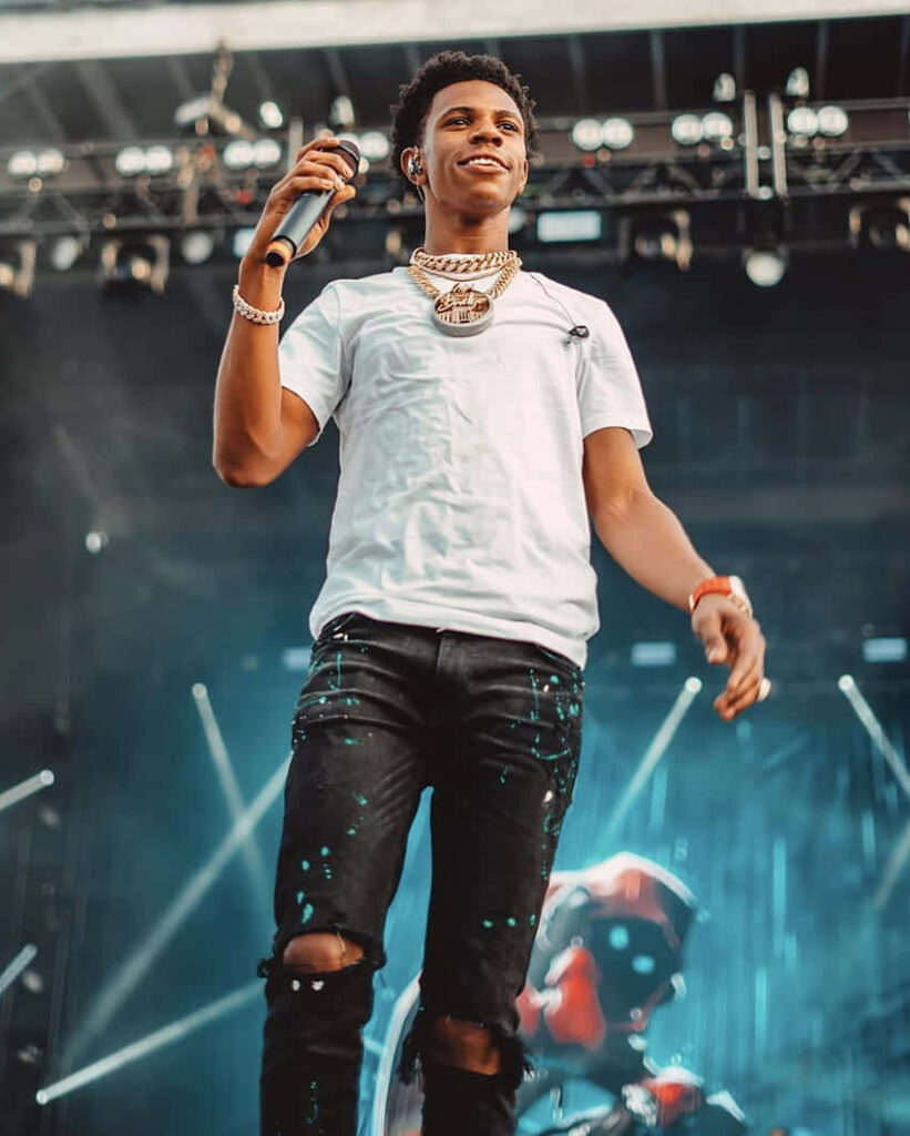 Big Boogie energetic live performance white t-shirt ripped jeans vibrant concert lights background Wallpaper
