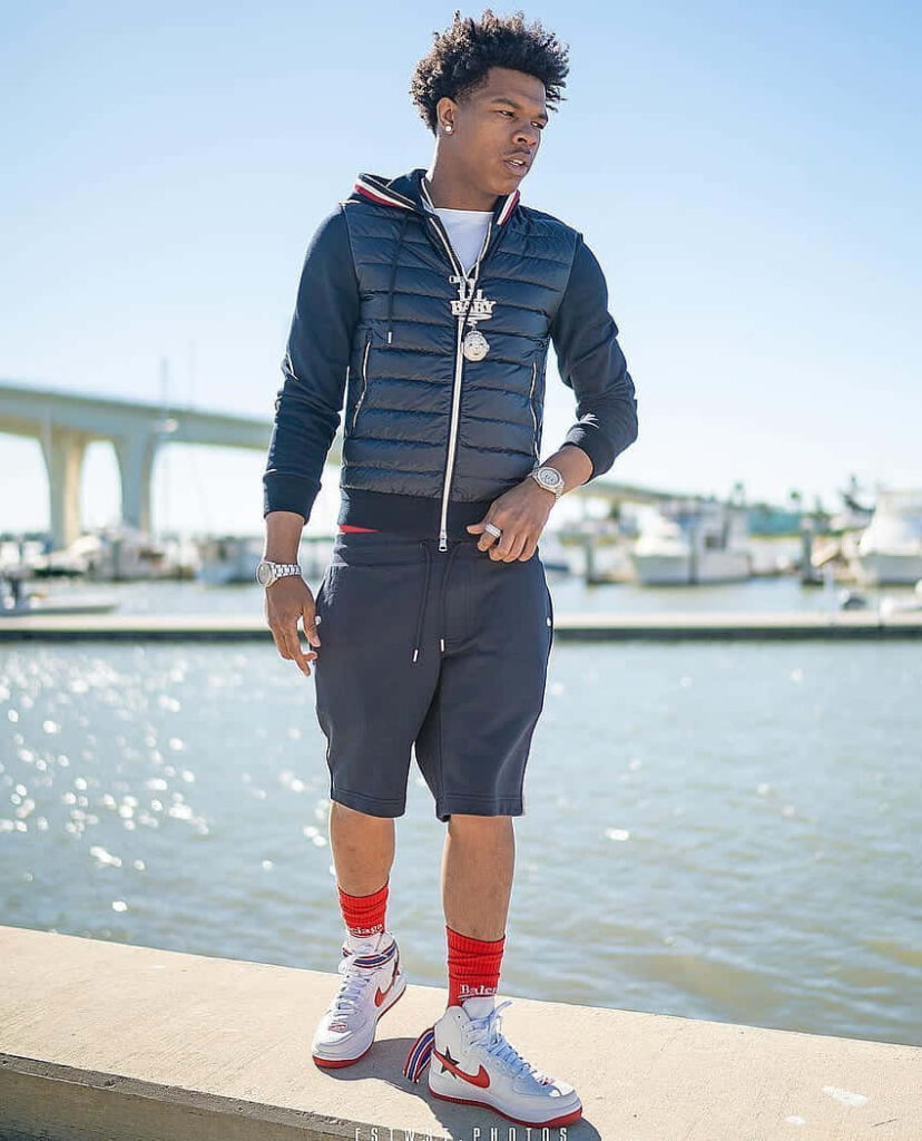 Big Boogie confident by waterfront in stylish outfit bold music personality wallpaper background