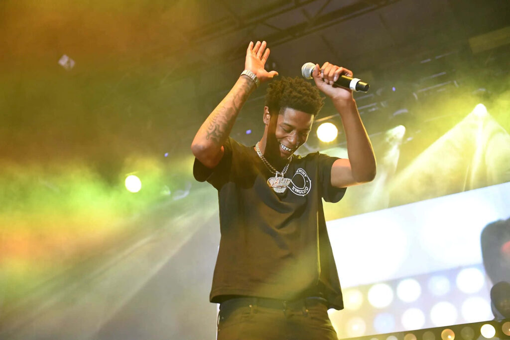 Big Scarr performing on stage with microphone and dynamic colorful lighting background wallpaper