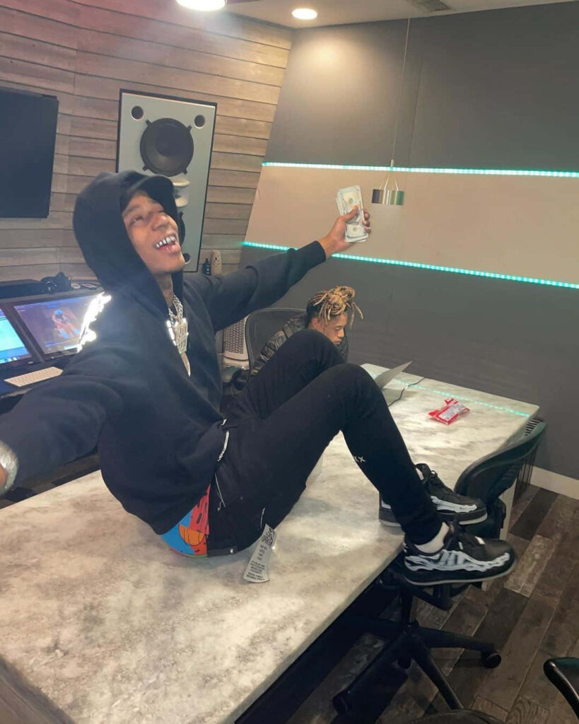 Big Scarr smiling energetically sitting on table in studio showcasing American rapper vibe wallpaper
