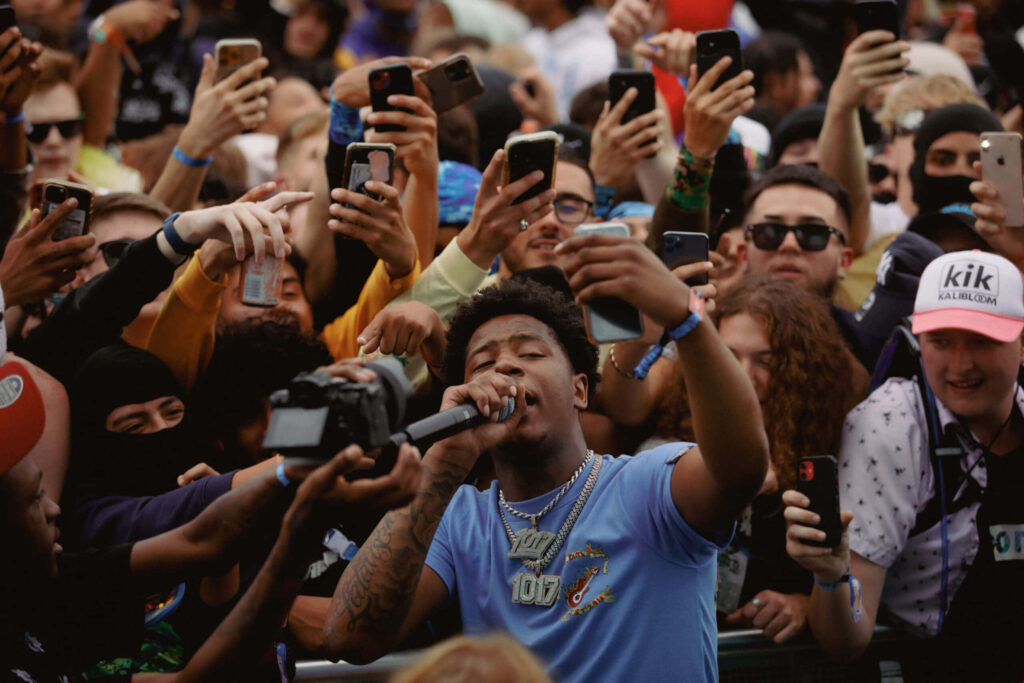 Big Scarr performs live on stage with fans capturing the energetic rap concert in background wallpaper