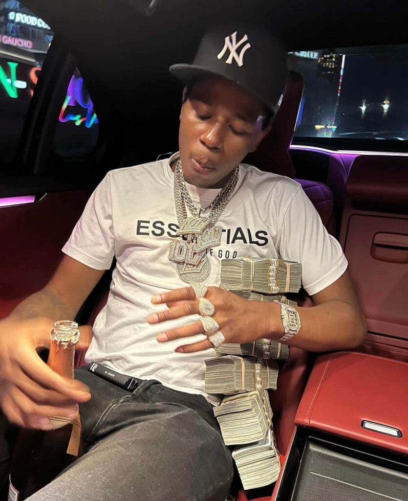 Big Scarr in luxury car wearing Essentials shirt New York Yankees cap with cash diamond jewelry Wallpaper