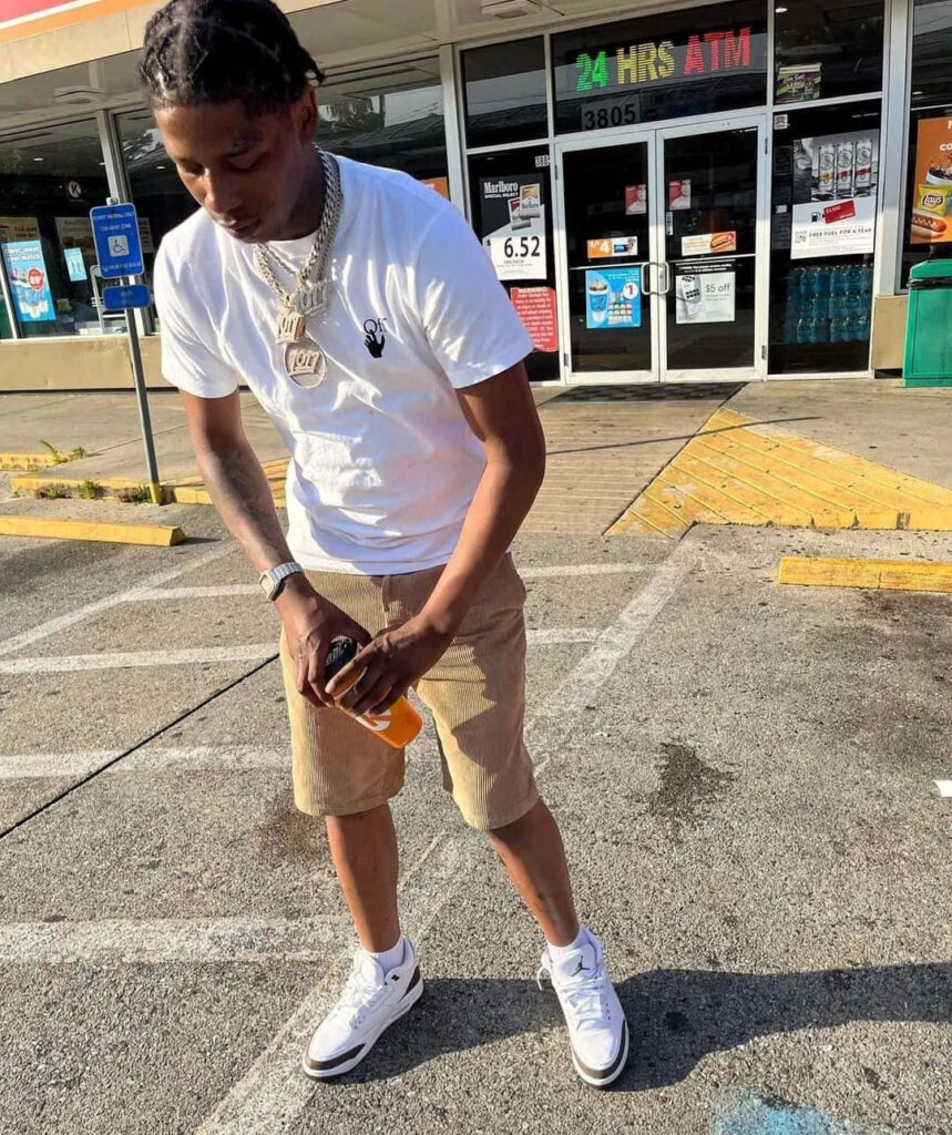 Big Scarr outside convenience store wearing white t-shirt beige shorts white sneakers rapper style Wallpaper