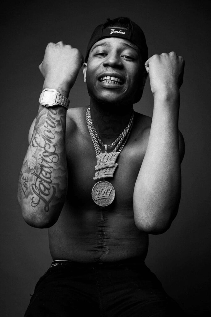 Big Scarr shirtless showing tattoos and jewelry posing confidently against dark background wallpaper