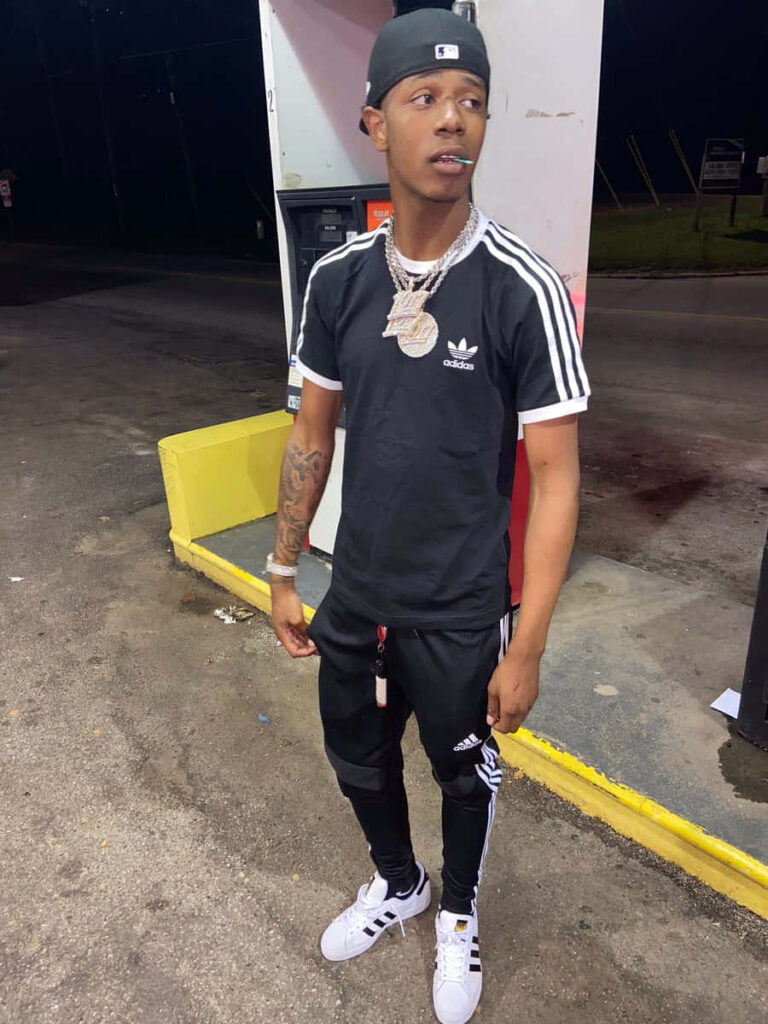 Big Scarr at night gas station wearing black Adidas outfit chains and cap American rapper style Wallpaper