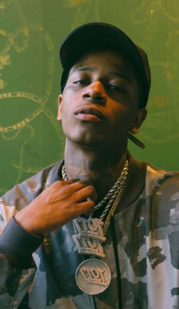 Big Scarr rapper with cap and chains on green graffiti background confident street style wallpaper
