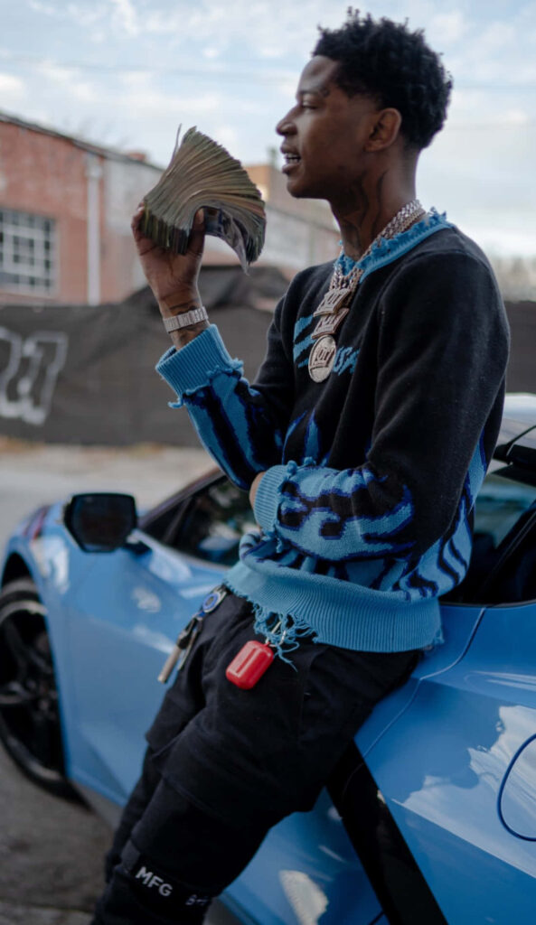 Big Scarr rapper with cash and jewelry beside blue sports car wallpaper background