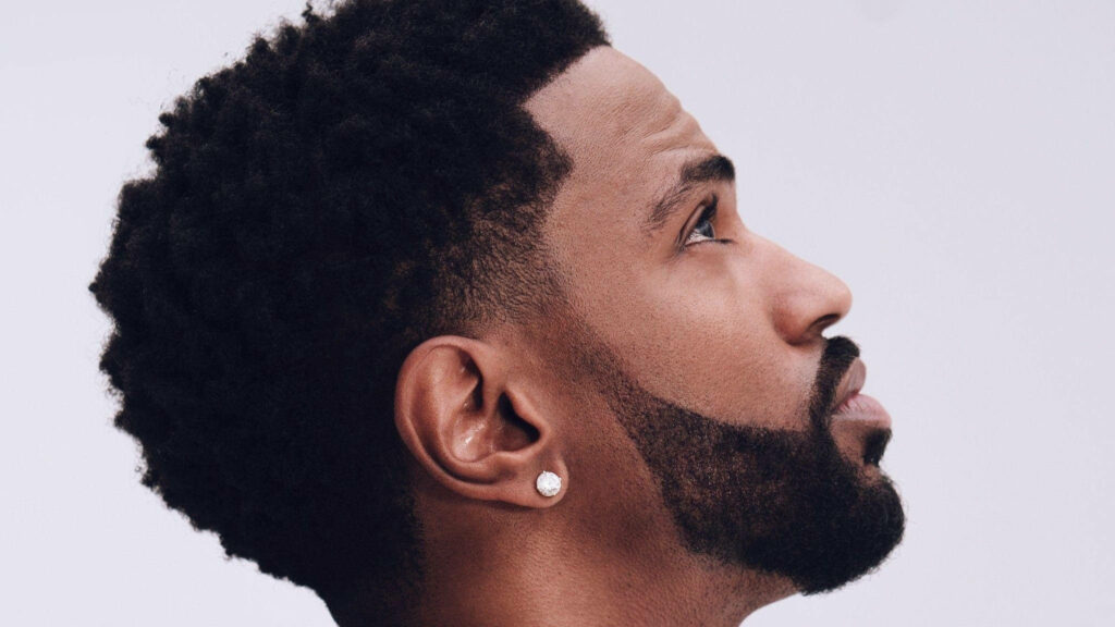 Big Sean looking upward with sharp profile and thoughtful expression on light wallpaper background