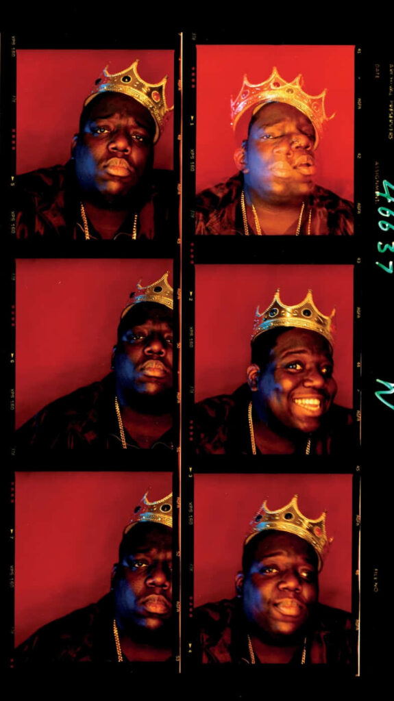 Iconic portraits of Biggie Smalls wearing golden crown on bold red background wallpaper