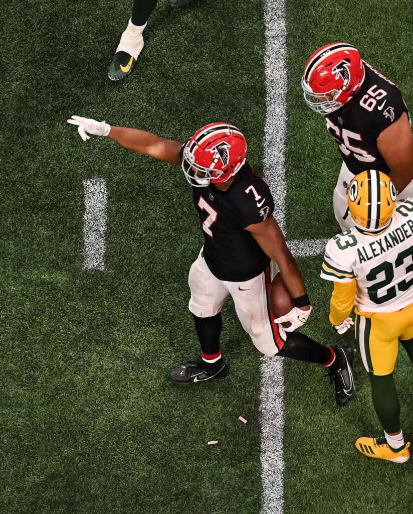 Bijan Robinson celebrating big play in Atlanta Falcons uniform on vibrant football field wallpaper