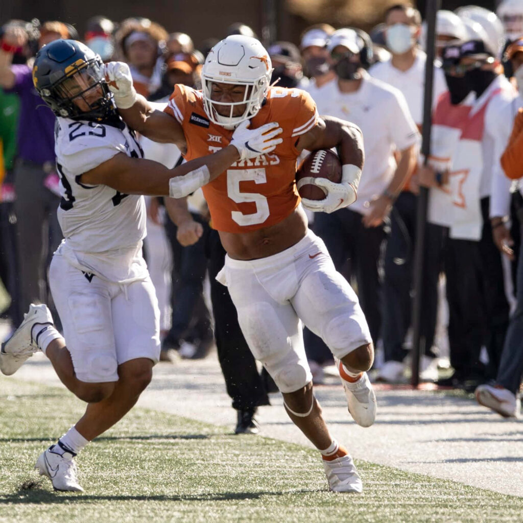 Bijan Robinson evades defender showcasing agility and strength in intense college football game wallpaper