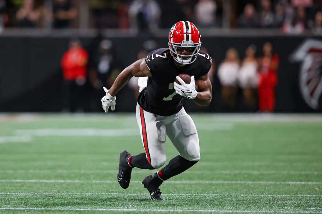 Bijan Robinson sprinting with football showcasing athleticism and determination dynamic wallpaper