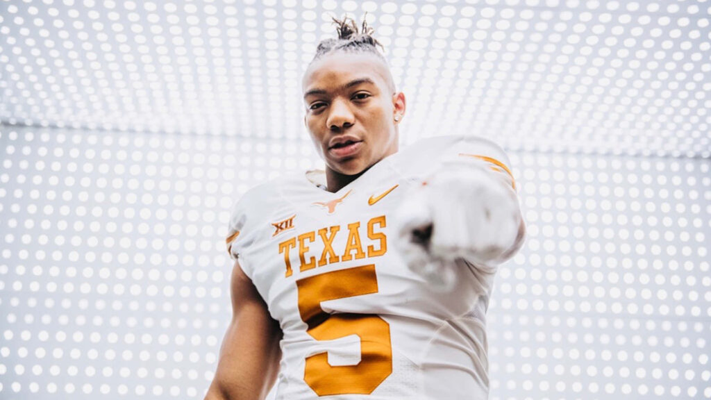 Bijan Robinson in Texas football uniform confidently pointing at camera bright modern backdrop Wallpaper