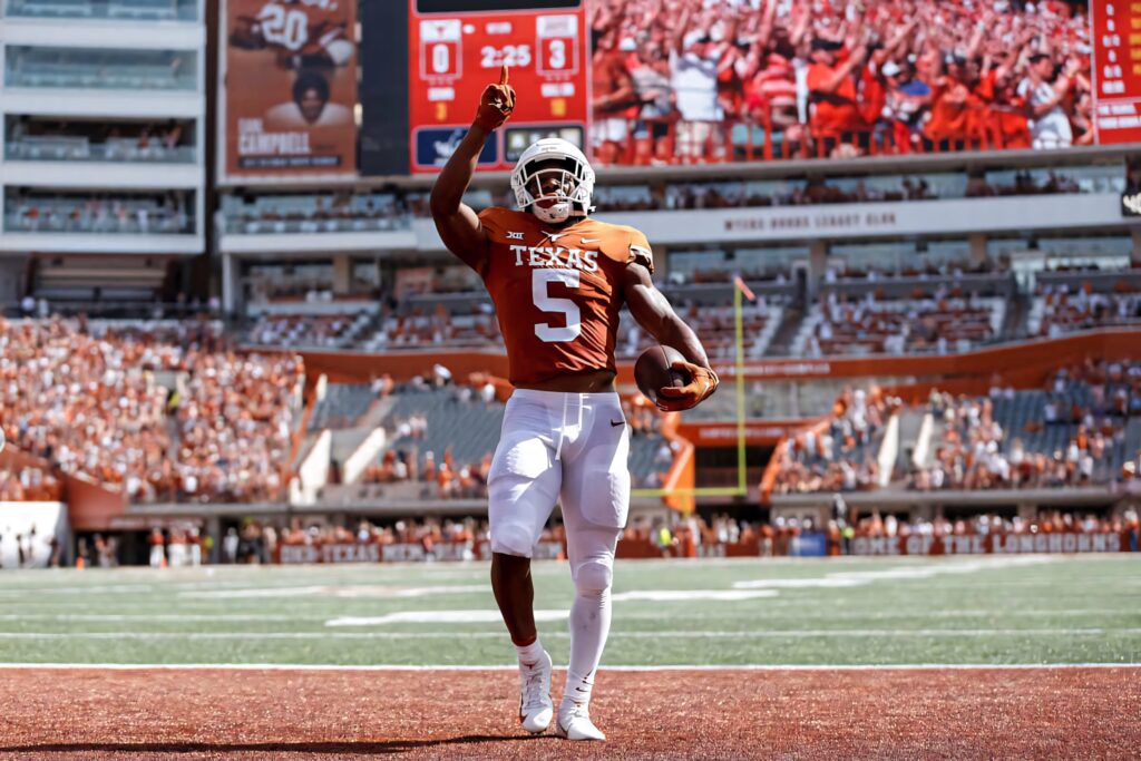 Texas Longhorns football star Bijan Robinson celebrates touchdown with energetic fans cheering Wallpaper
