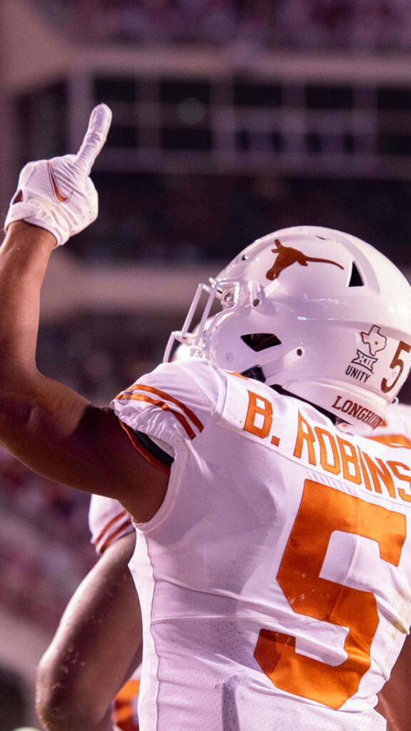 Bijan Robinson Texas Longhorns celebrating on field hand raised victory inspiring wallpaper