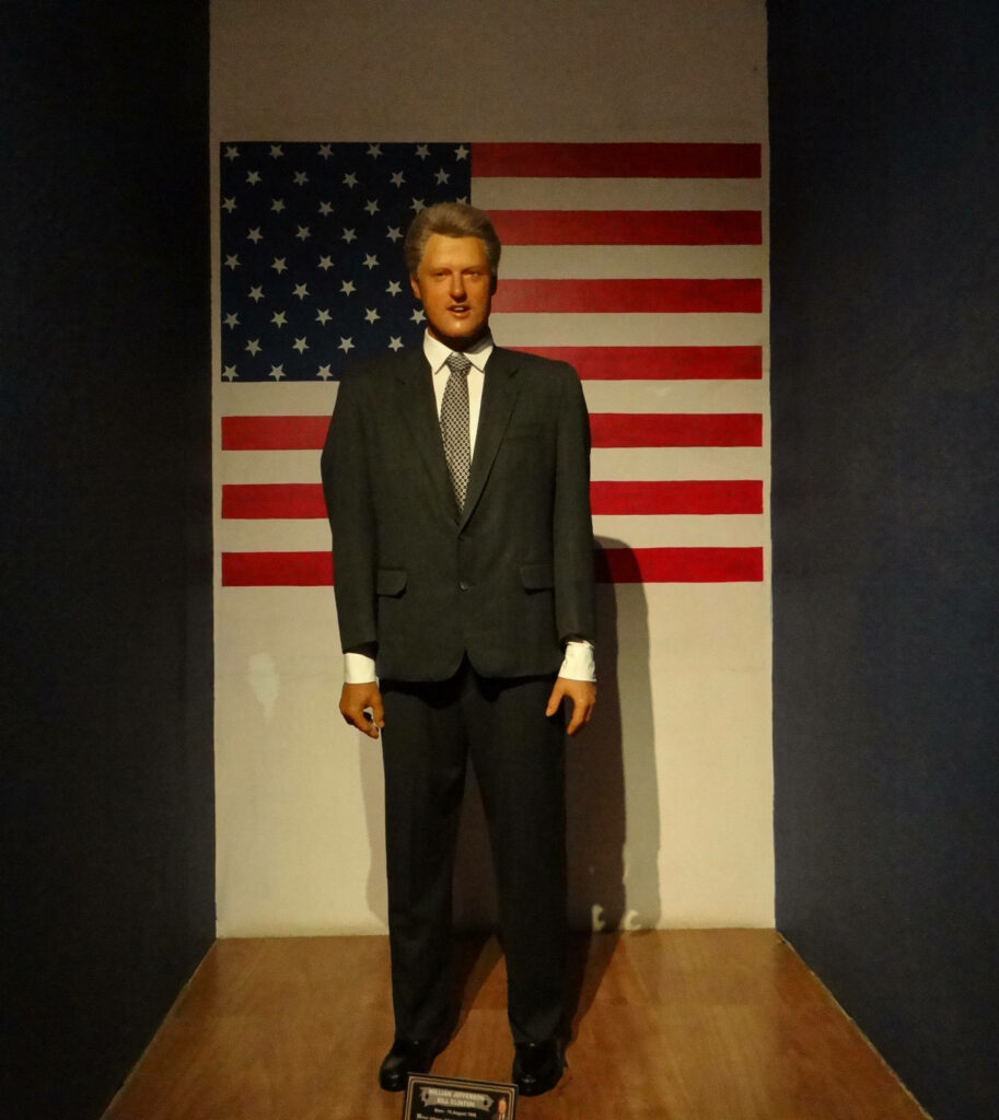 Former US President Bill Clinton delivering speech in front of American flag backdrop wallpaper