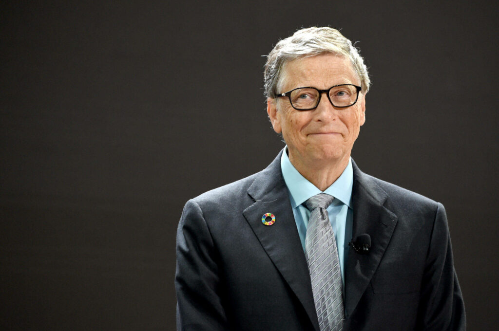 Bill Gates in suit and tie with calm thoughtful expression on dark wallpaper background