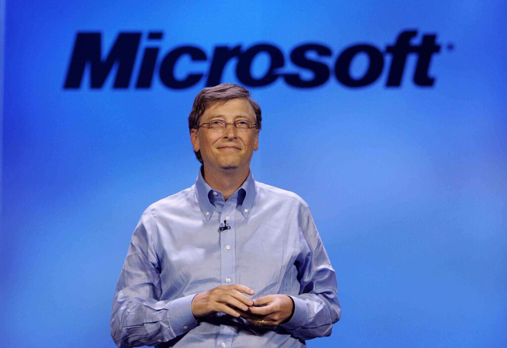 Bill Gates standing confidently before large Microsoft logo inspiring tech leadership wallpaper