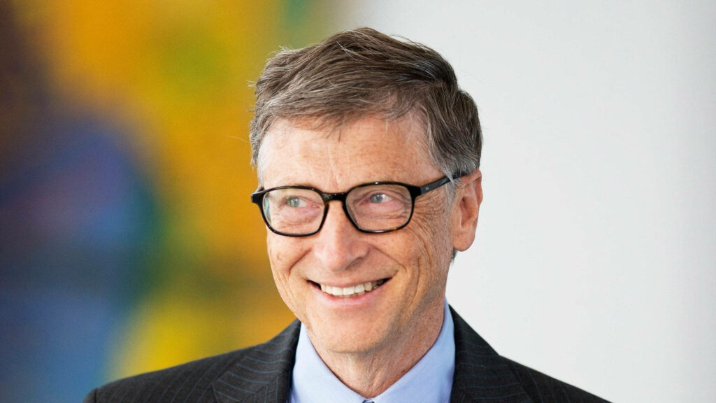 Bill Gates smiling warmly in suit and glasses with colorful vibrant blurred background wallpaper