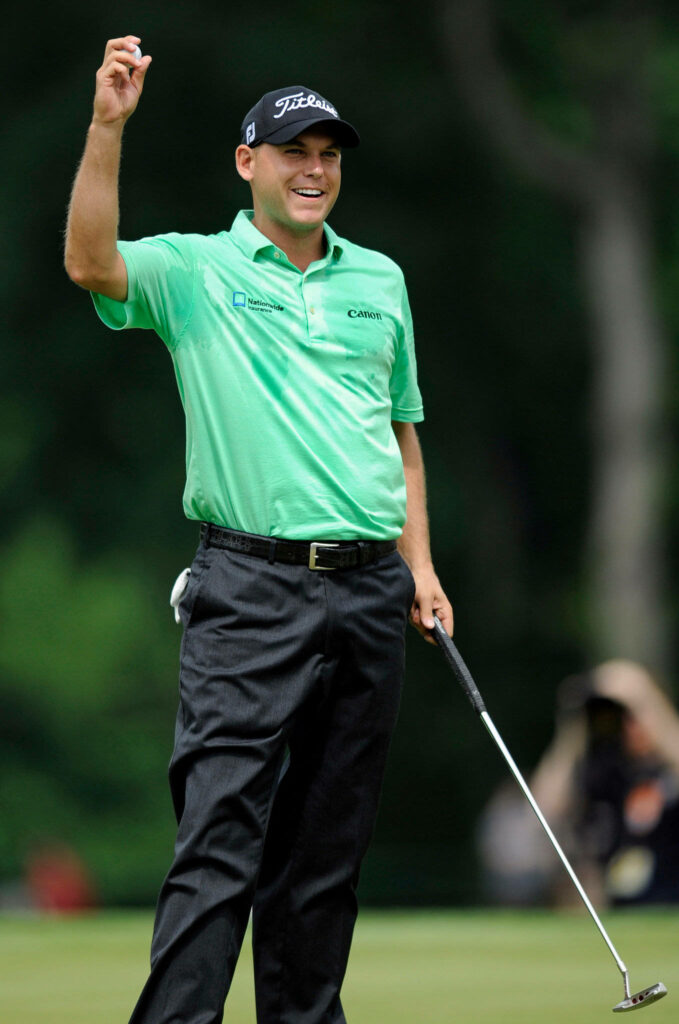 Bill Haas celebrating on golf course wearing green shirt black pants holding putter smiling Wallpaper