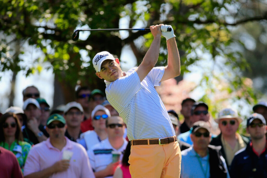 Bill Haas concentrates on his golf swing with a crowd cheering at a scenic golf course background Wallpaper