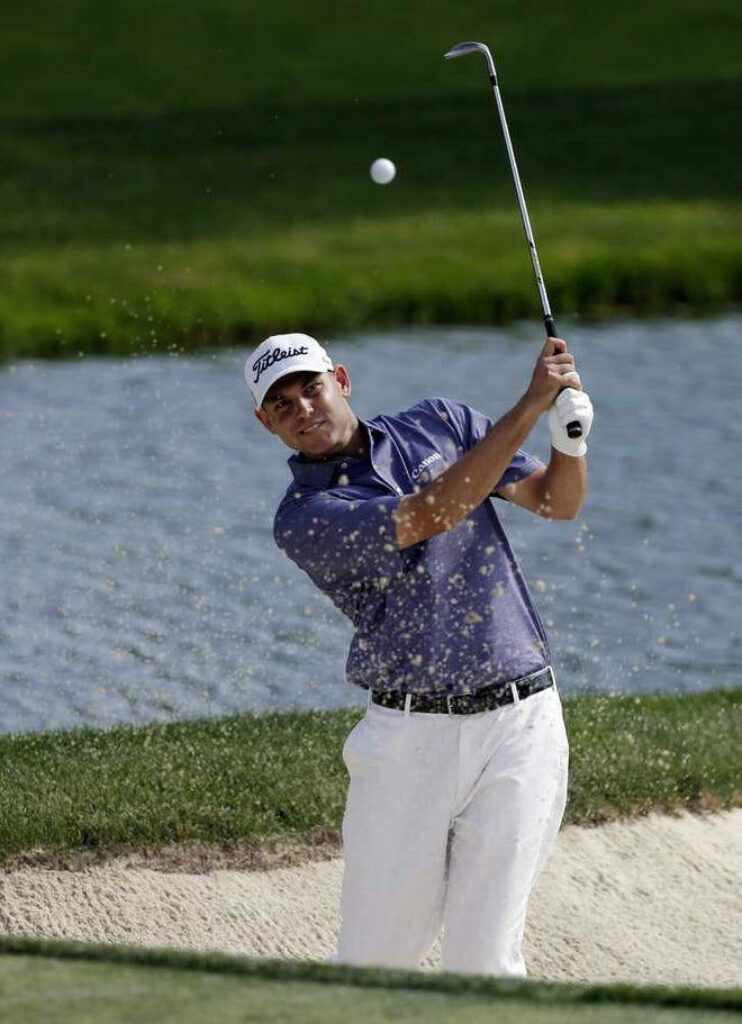 Bill Haas powerful golf swing with flying sand near water hazard dynamic golf wallpaper background