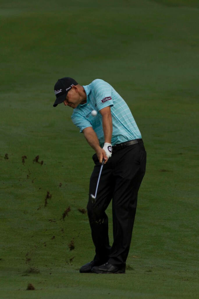 Bill Haas powerful golf shot with turf flying focused dynamic presence on golf course wallpaper