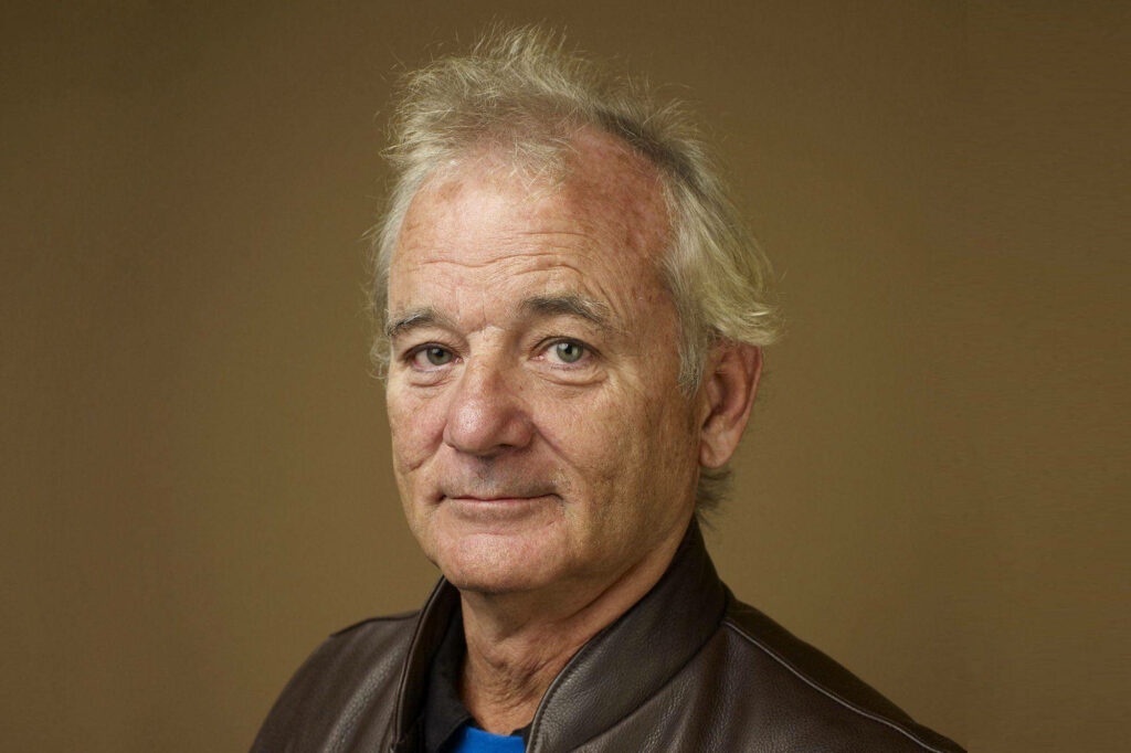 Warm portrait of Hollywood celebrity Bill Murray with gentle smile on brown wallpaper background