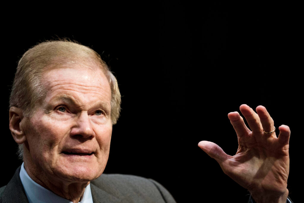 Bill Nelson raising hand portrait against black backdrop dramatic focused wallpaper background