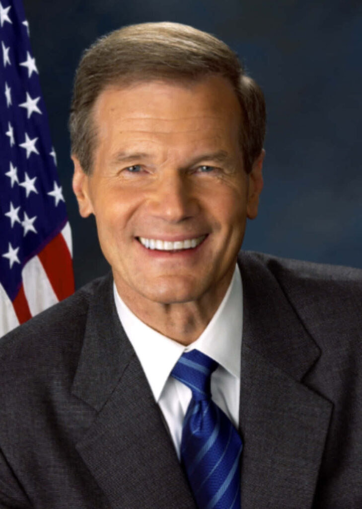 Former Senator Bill Nelson smiling in professional portrait with American flag background wallpaper