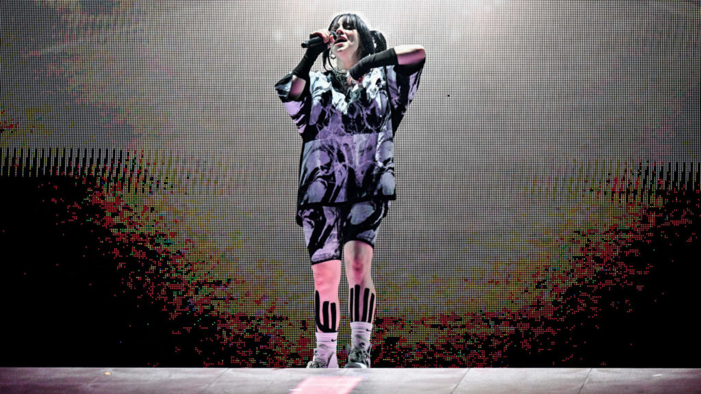 Billie Eilish Dynamic Stage Performance - Captivating Wallpaper Background