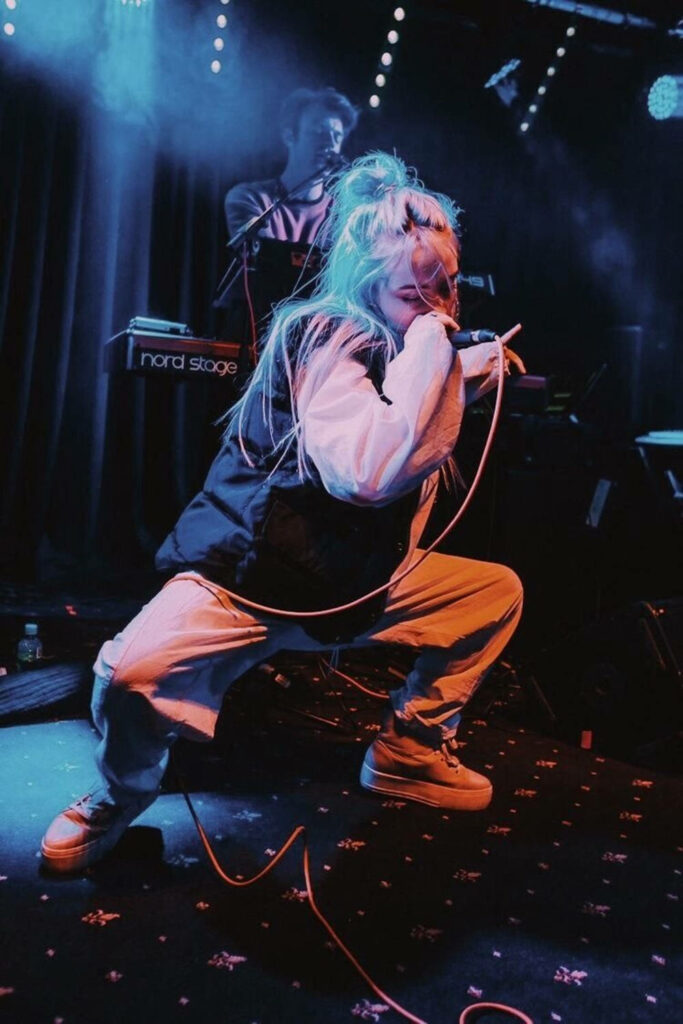 Vibrant Billie Eilish Wallpaper: Energetic Stage Performance Background
