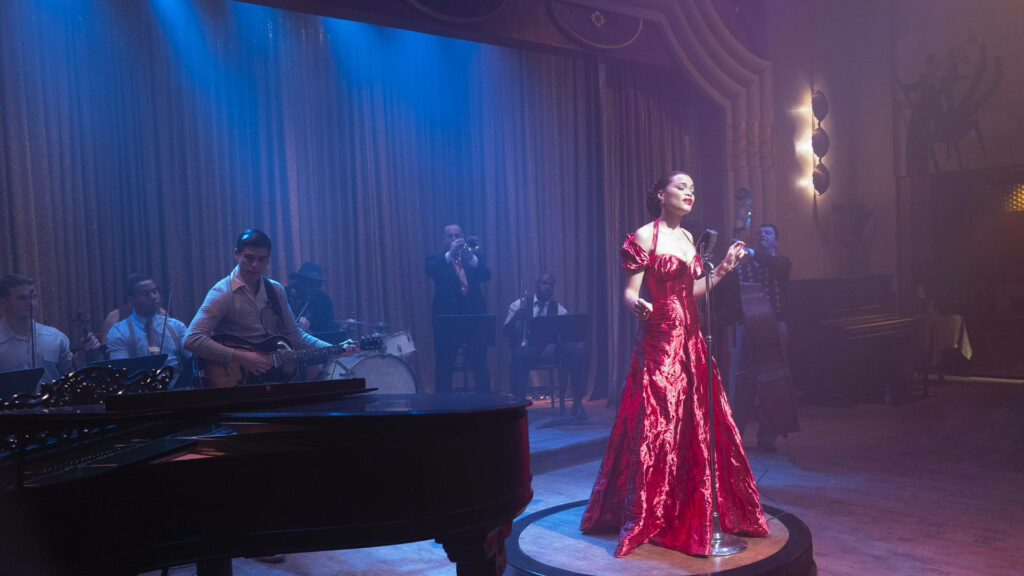 Billie Holiday in glamorous red dress singing onstage with live jazz band under soft lights Wallpaper