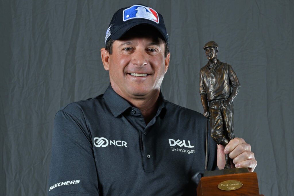 Billy Andrade smiling proudly holding golf trophy celebrating golfing victory with plain background Wallpaper